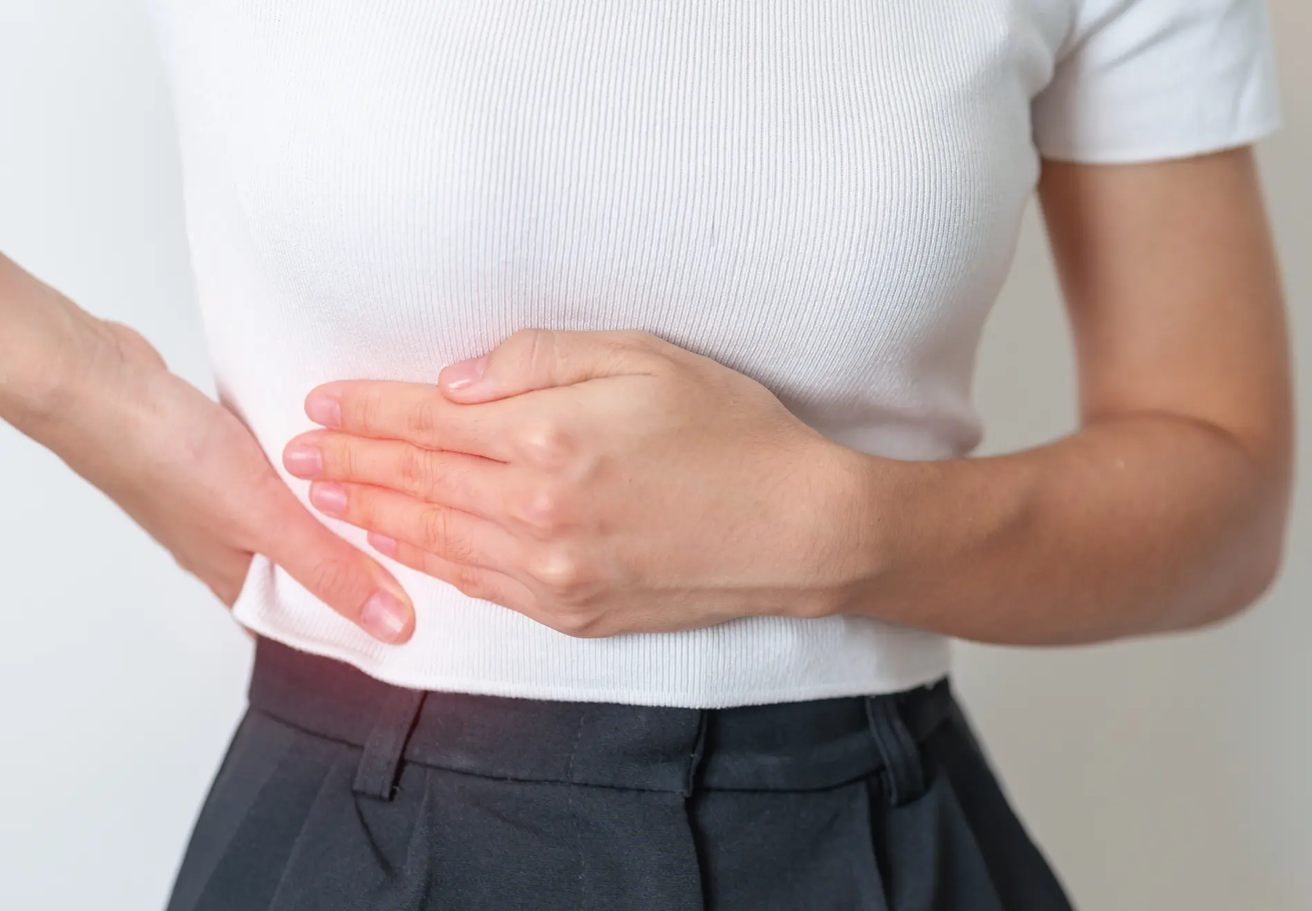 Woman holding upper right abdomen experiencing liver or side pain.