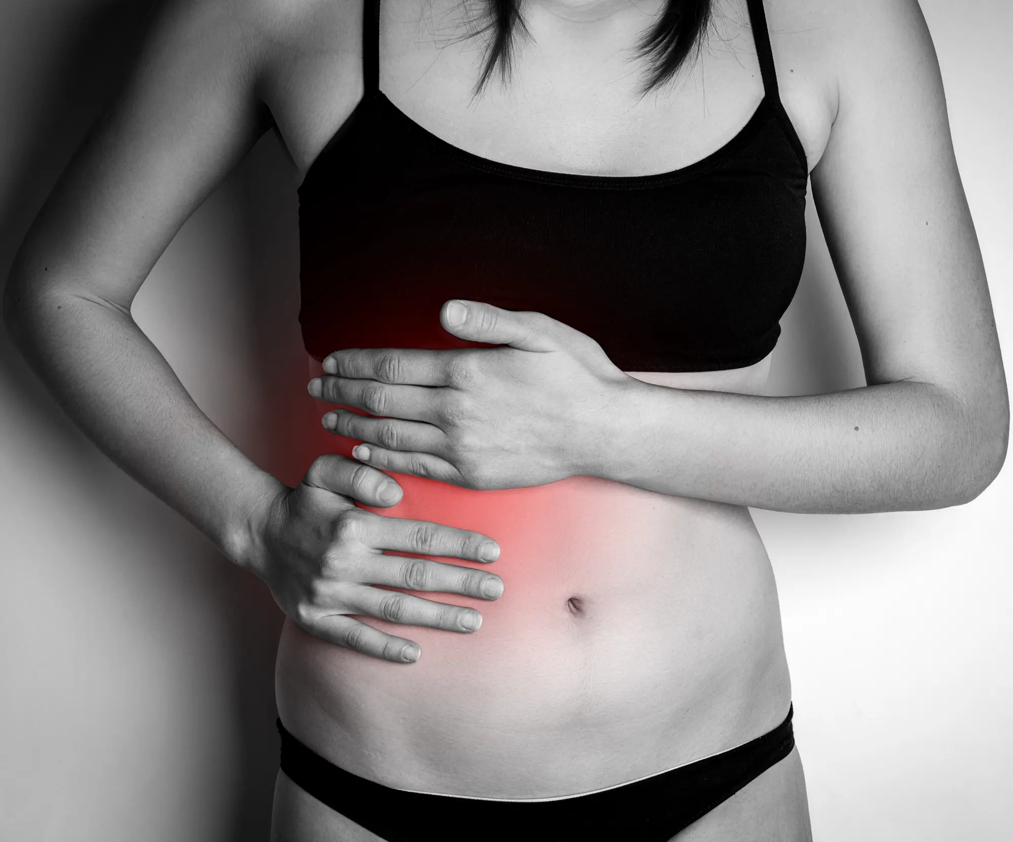 Woman holding stomach with both hands over inflamed liver.