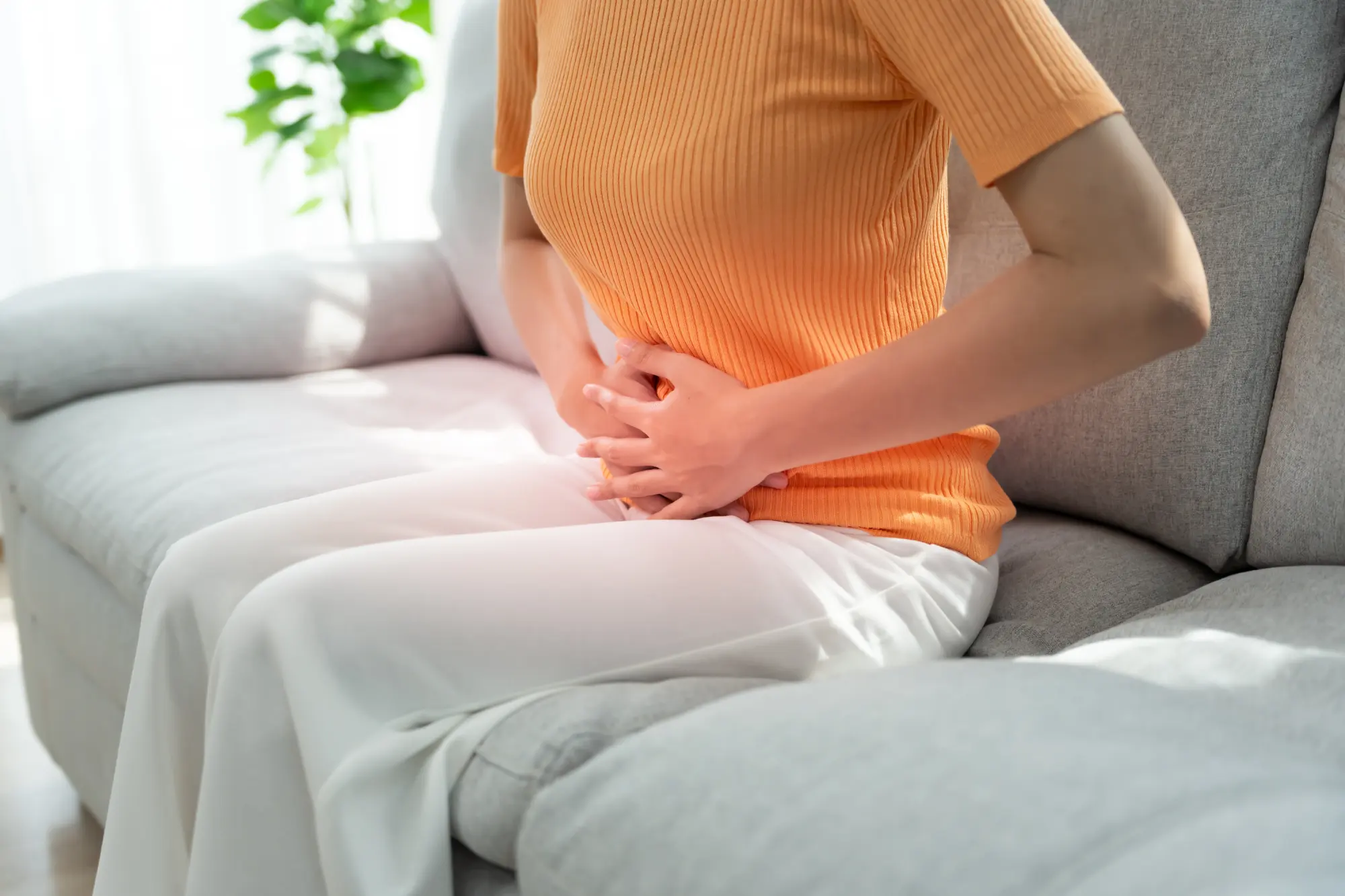 Woman sitting on a couch holding her stomach.
